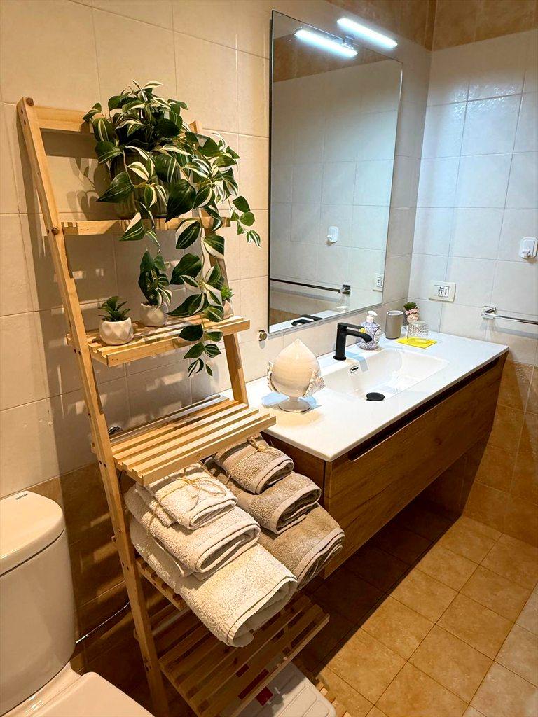 Il secondo bagno rinnovato: mobile in legno chiaro, lavabo bianco, specchio grande e scaletta portasciugamani