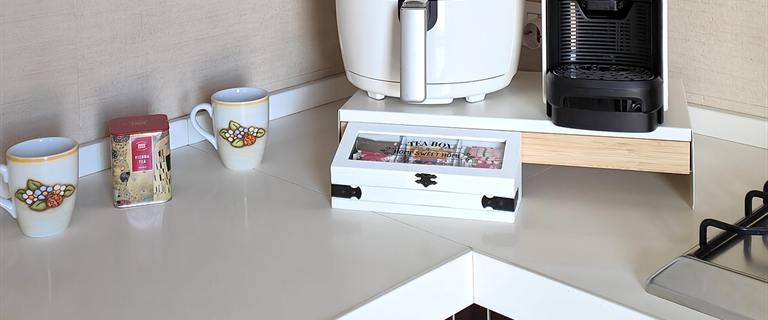Il piano della cucina di Casa Plac: due tazze a fiori, una latta di tè, il cofanetto delle bustine e la macchina del caffè