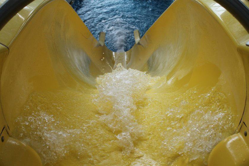 Vista dall'interno di uno scivolo giallo di un parco acquatico, con l'acqua che schizza